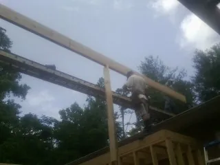 Carpenter setting a ridge beam over a new addition frame — Ice Dam Removal by Roofing Brothers in Dunedin