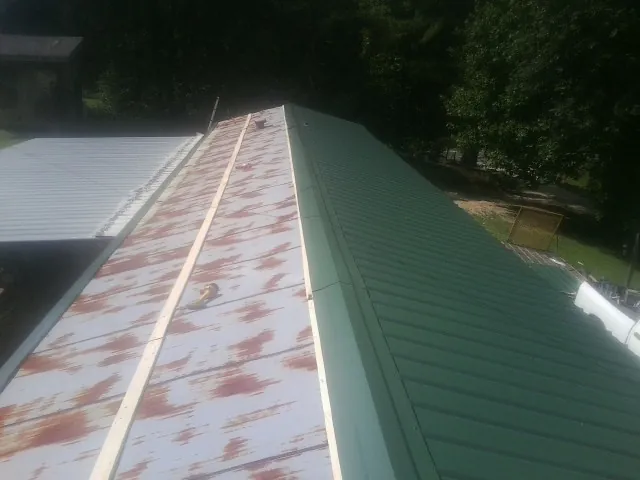 Old rusted panels beside newly installed green metal roofing — Wind Damage Roof Repair by Roofing Brothers in Dunedin