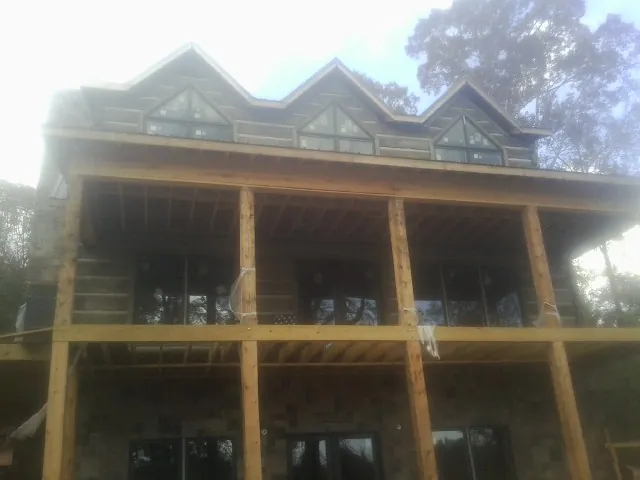 Dormers and porch framing on a large log home under construction — Roof Coating work by our crew in Dunedin