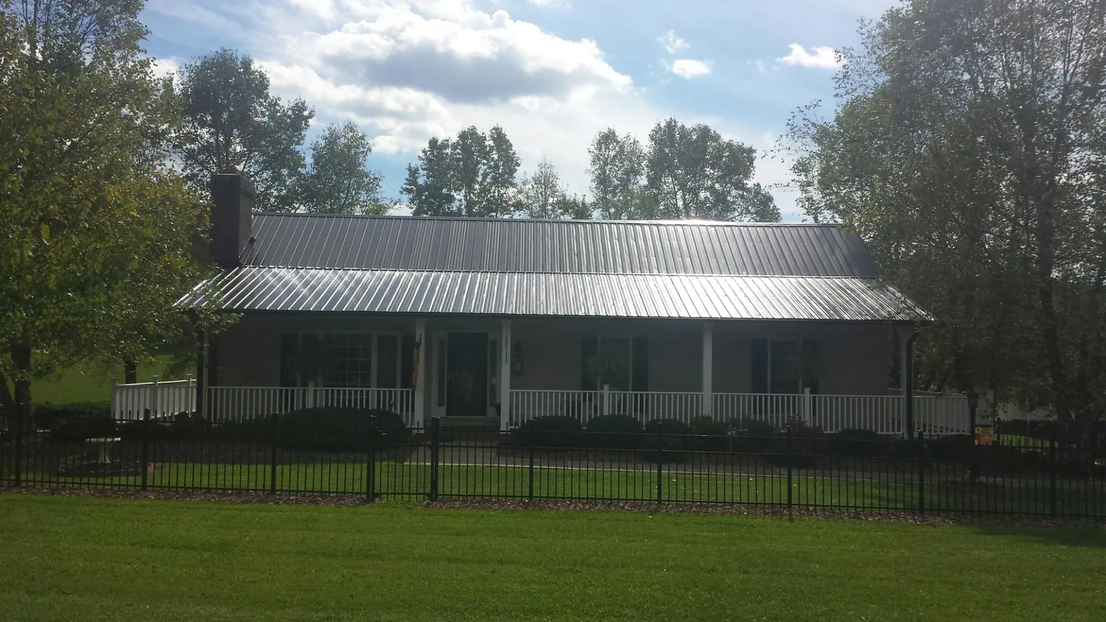 Gray metal roof on a brick ranch with a full width front porch — Gutter Guard Installation work by our crew in Dunedin