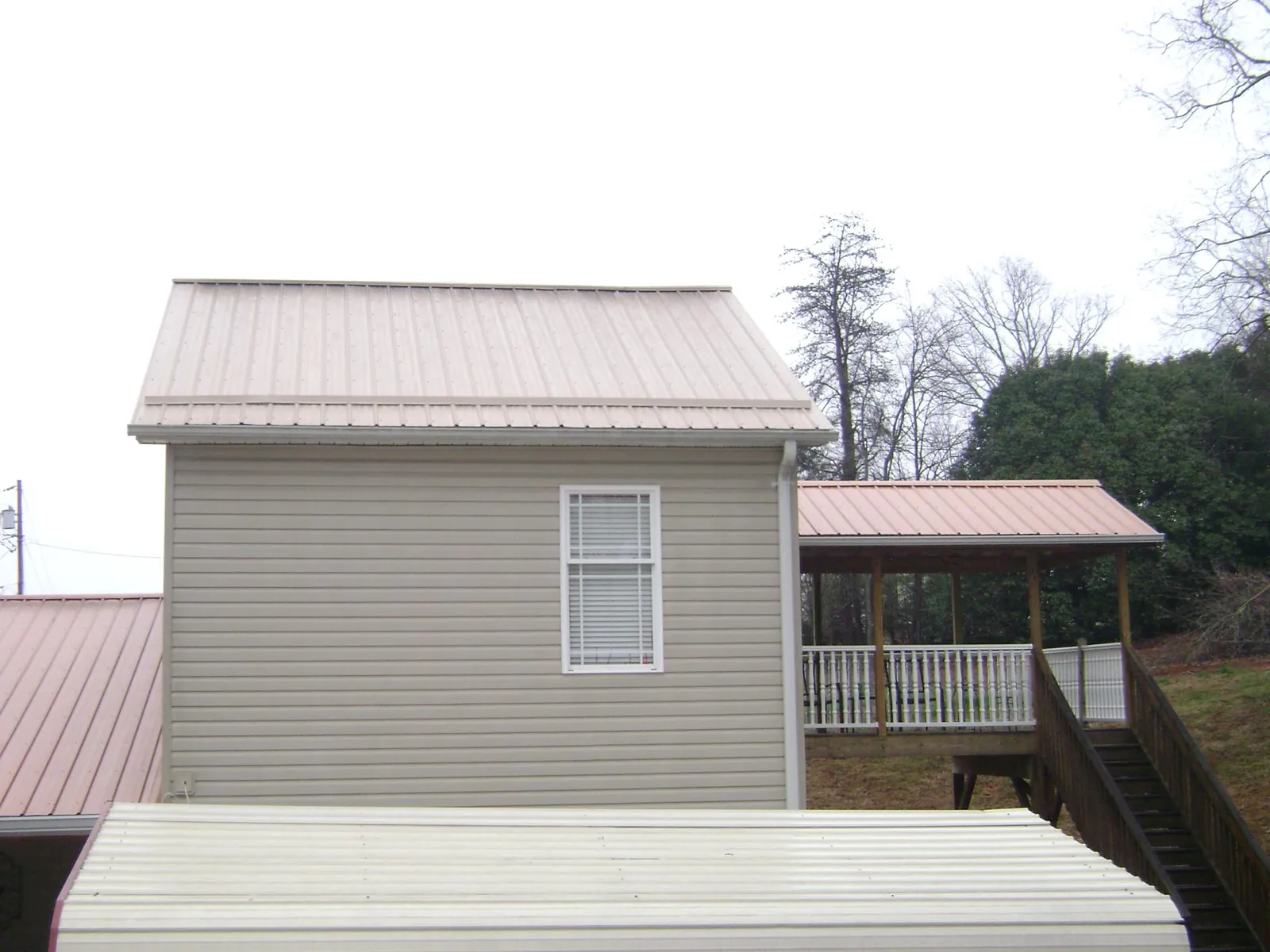 Tan metal roofs on a two story addition and attached porch, from a Roof Replacement job in Dunedin